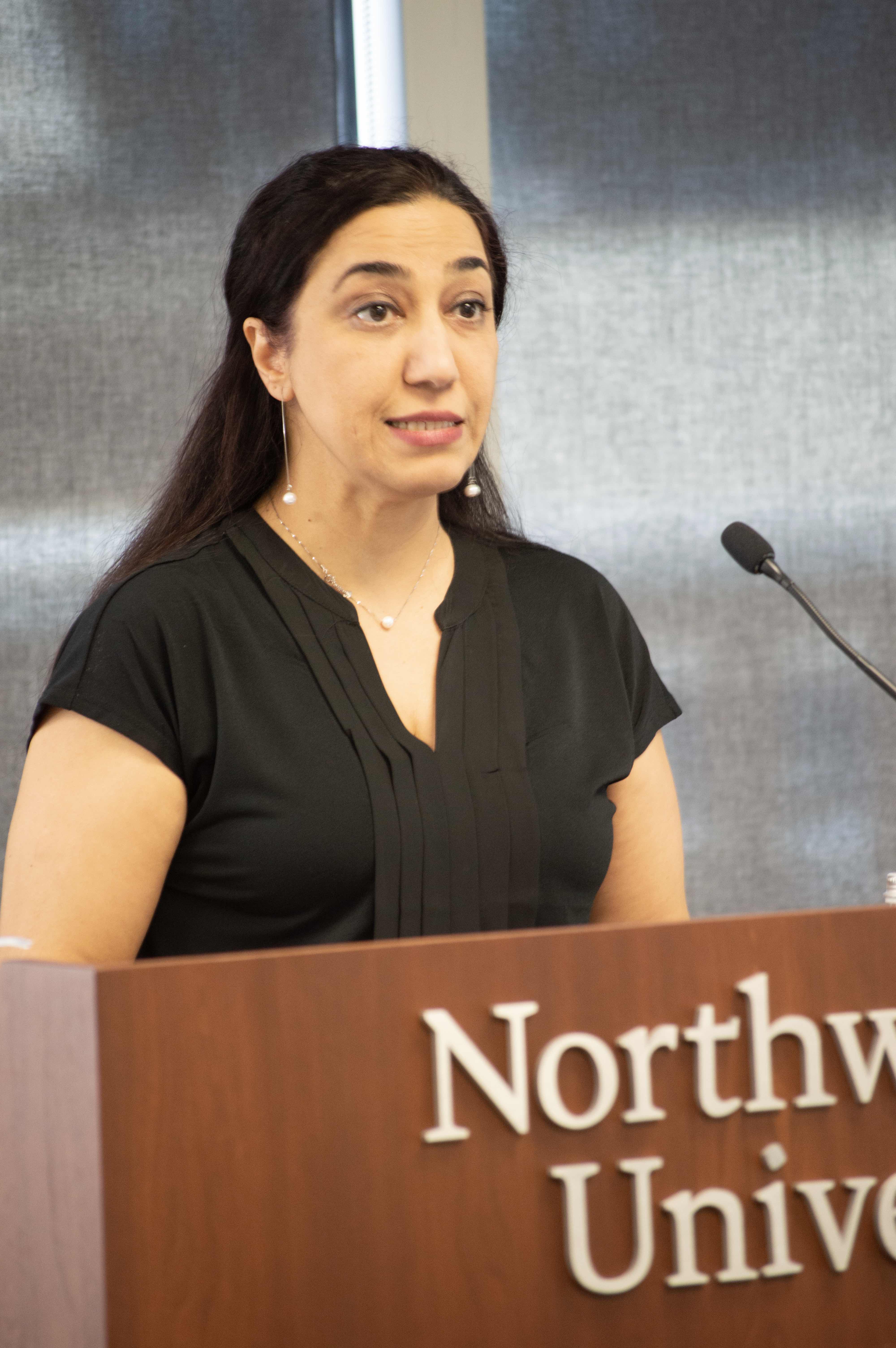 a woman standing at a podium, speaking