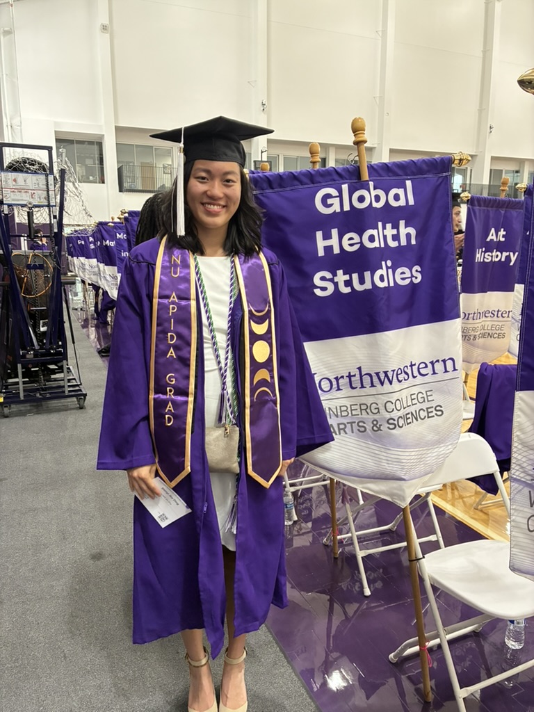 GHS Student Marshal Shinyi Ding standing next to the GHS banner