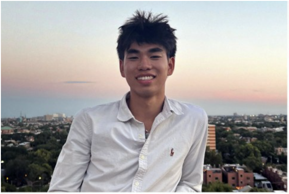 a young asian man standing outside during a sunset, smiling