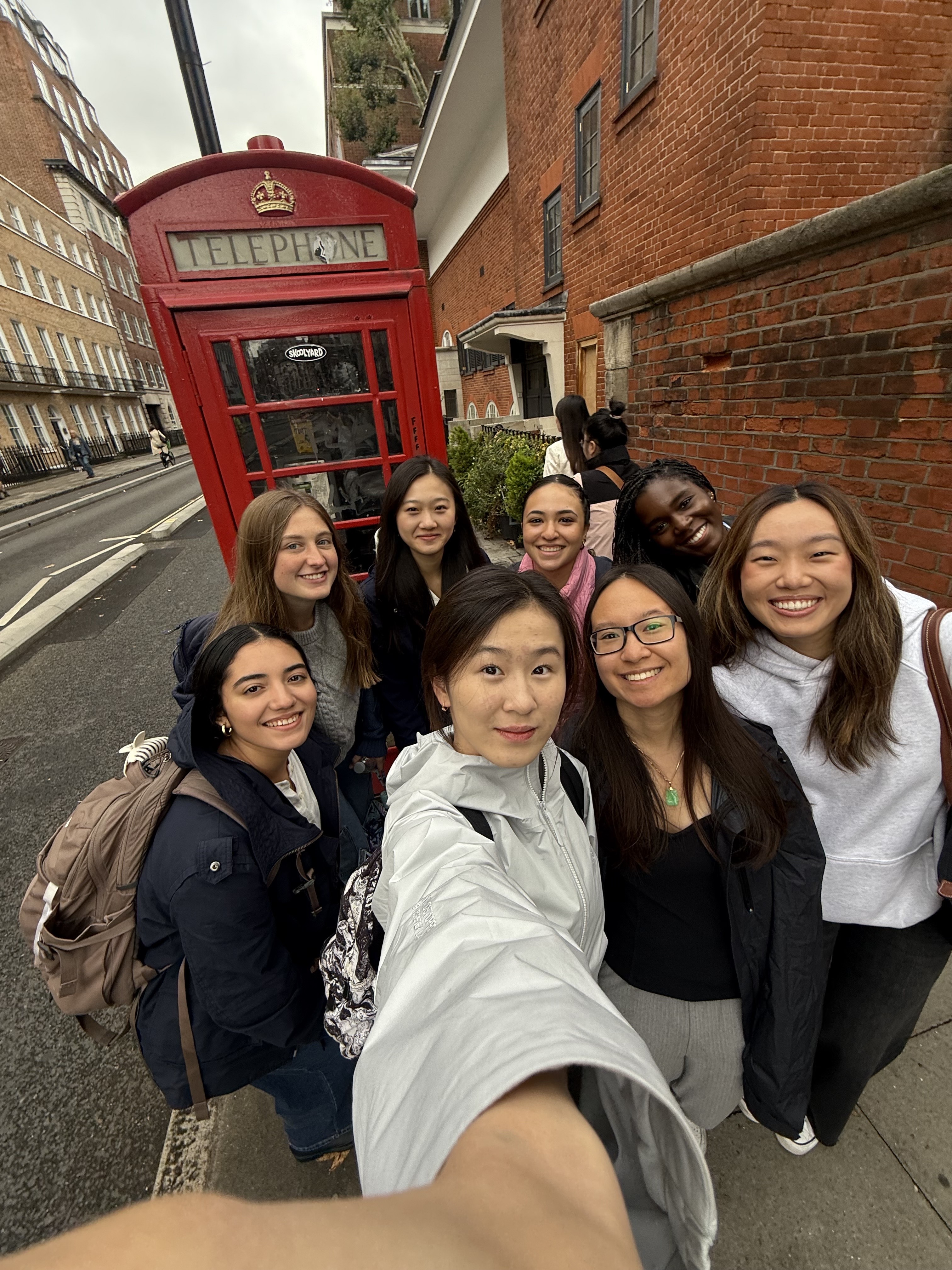 A group of female students taking a selfie in front of a red phonebooth.