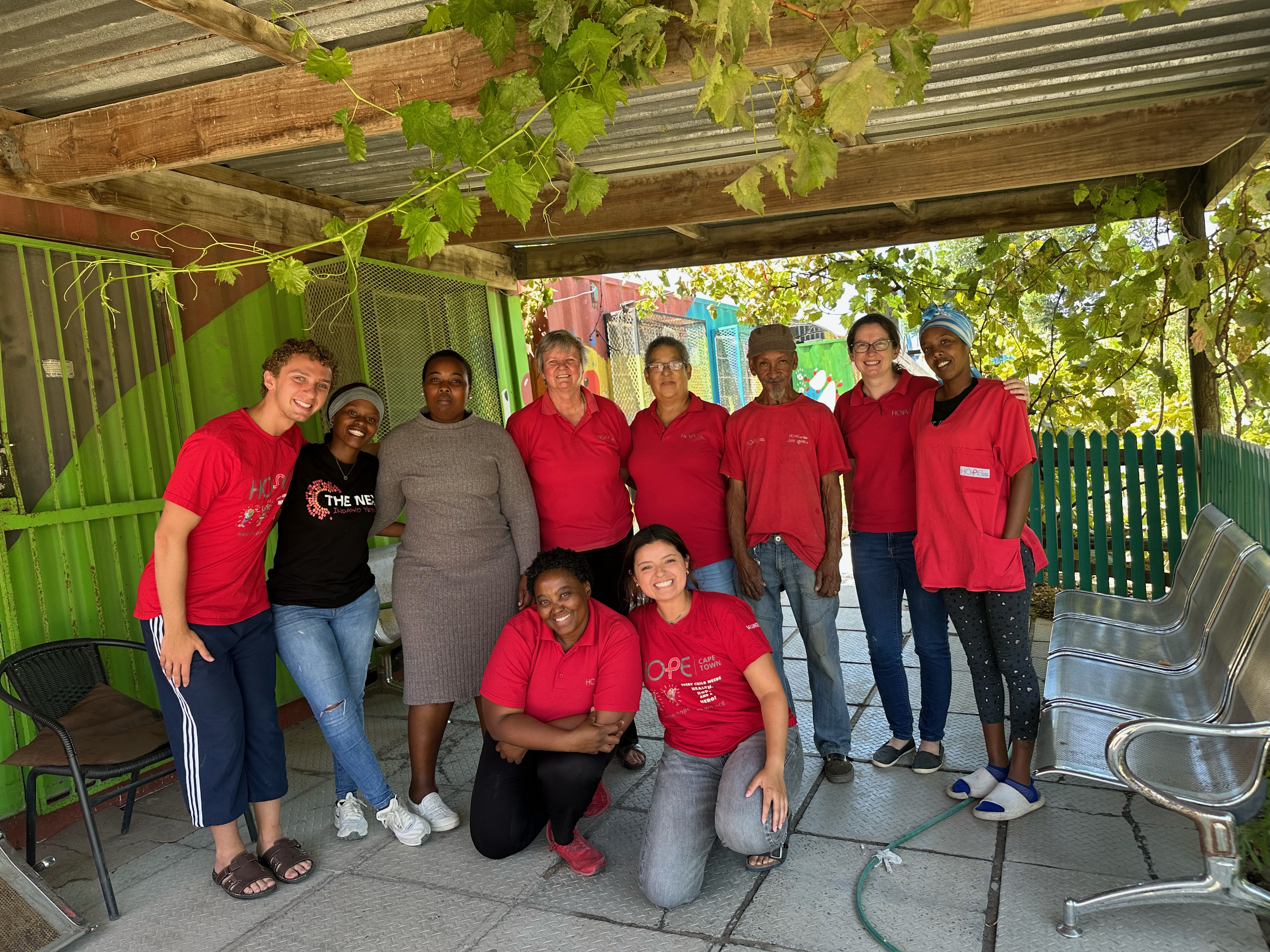A group of people with mostly red t-shirts standing outside under a gazebo